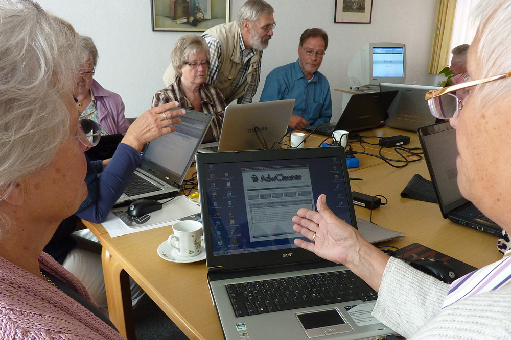 Eine Gruppe an Senioren, die an Laptops arbeiten